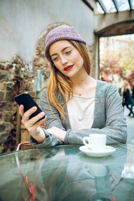 年轻女子一边喝咖啡一边使用智能手机的肖像