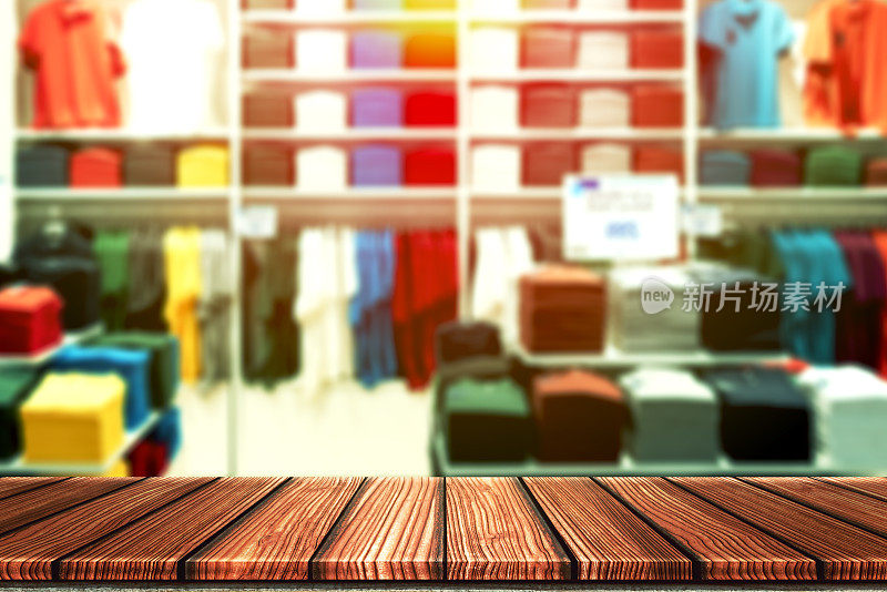 木制的桌子与模糊的背景休闲精品店，衬衫品牌outlet或彩色服装店的产品展示蒙太奇。以时尚产品零售业务为网络营销背景。