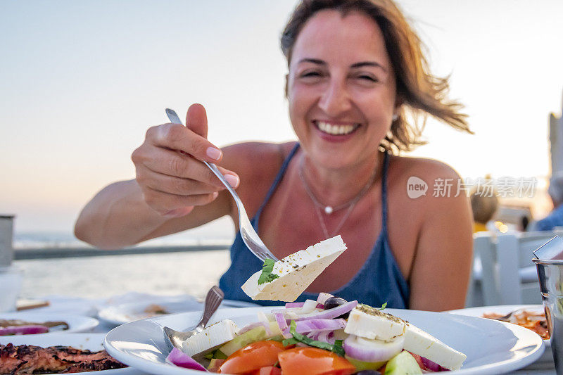 希腊女人享受美味的希腊食物和茴香酒。