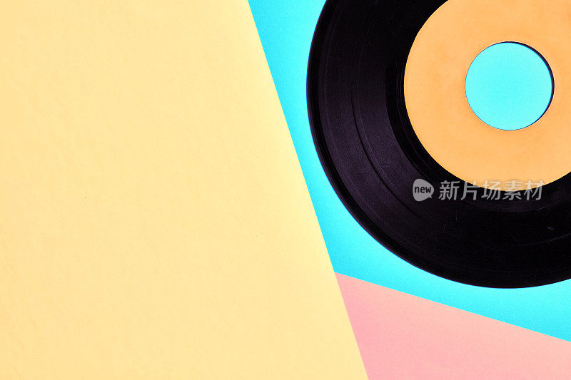 黑胶唱片在柔和的蓝色，黄色和粉红色的背景
