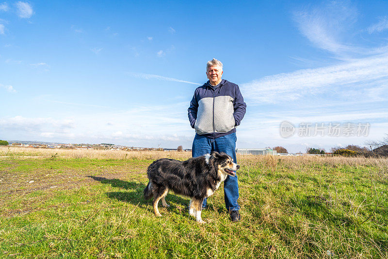 一名男子和边境牧羊犬在草原上散步