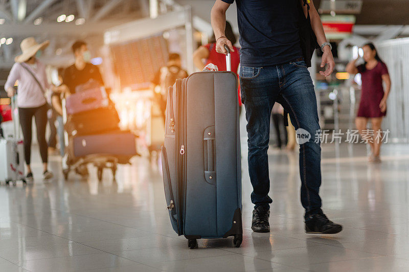 在现代机场航站楼，旅客们拖着行李步行前往新的地方。后面的观点。副本的空间。行李，旅行者，旅游，机场，步行，度假概念。