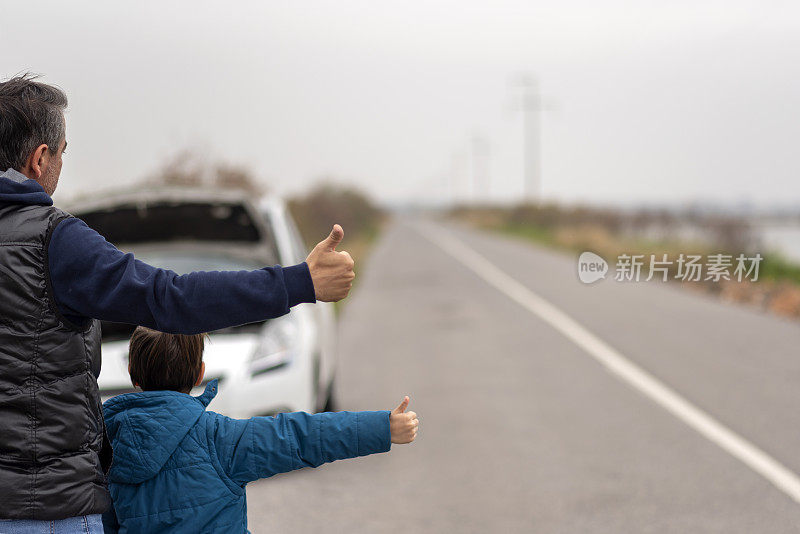 一个无助的男人和他的儿子在车旁