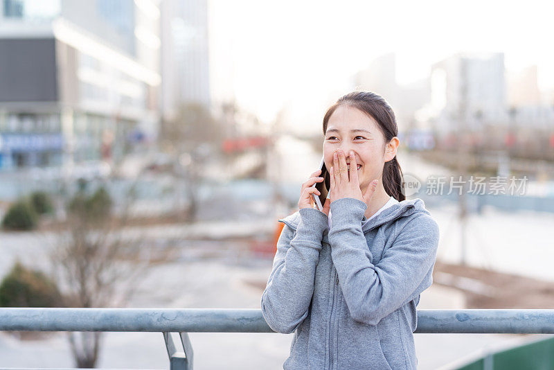 亚洲年轻女子在城市公共广场使用手机