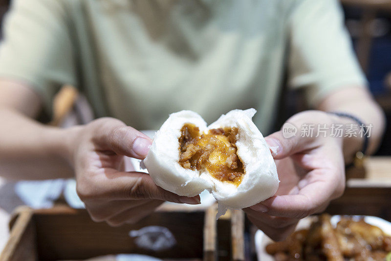 一位亚洲妇女正在一家广东餐馆里撕茶烧包