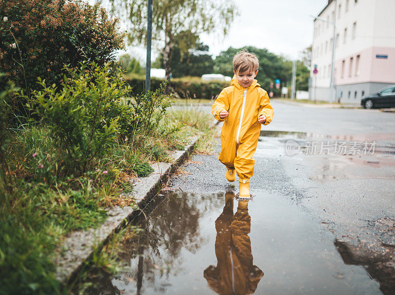 小男孩在雨中玩耍，跳进水里画画