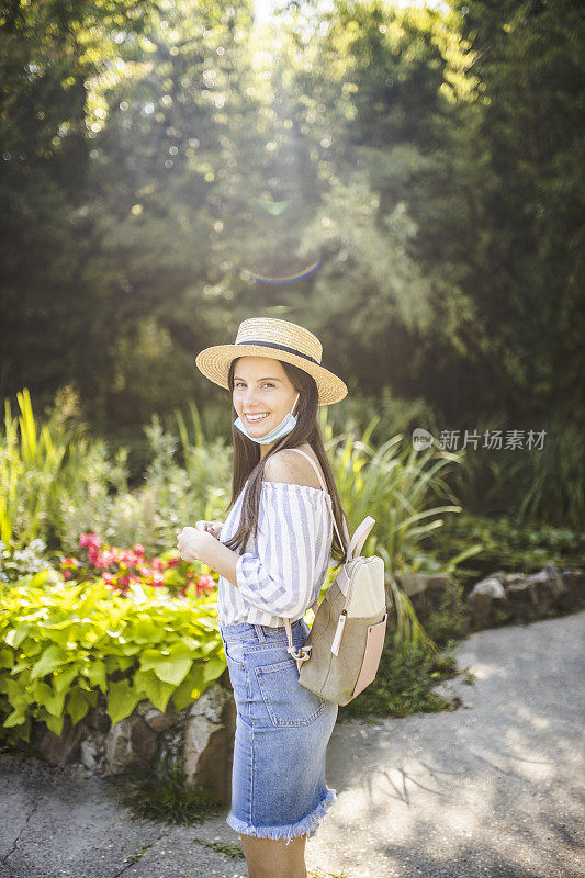 在冠状病毒大流行期间，戴着防护面罩的美丽女子在大自然中度过时光