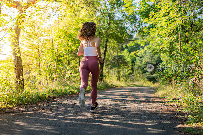 年轻的女运动员慢跑穿过森林。