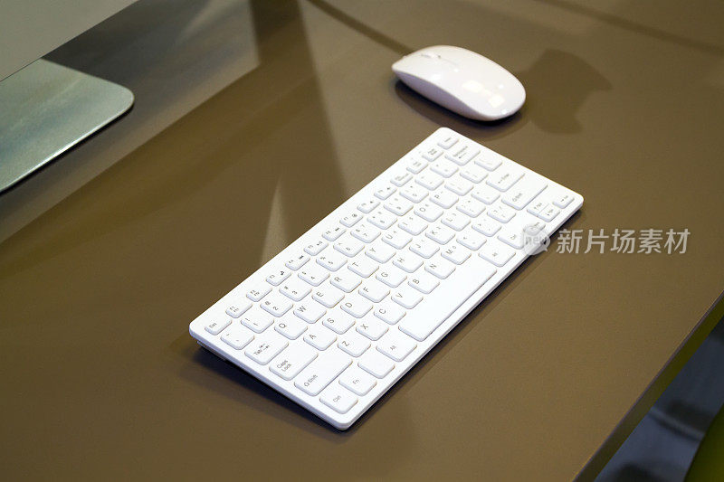 近距离观看米色书桌与白色键盘和鼠标旁边显示