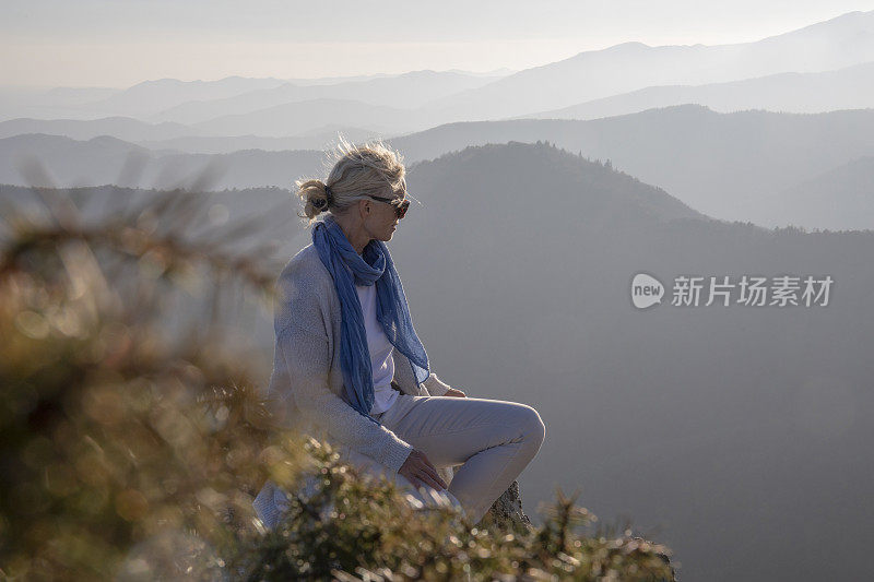 清晨，女徒步旅行者在阳光明媚的山脊上放松