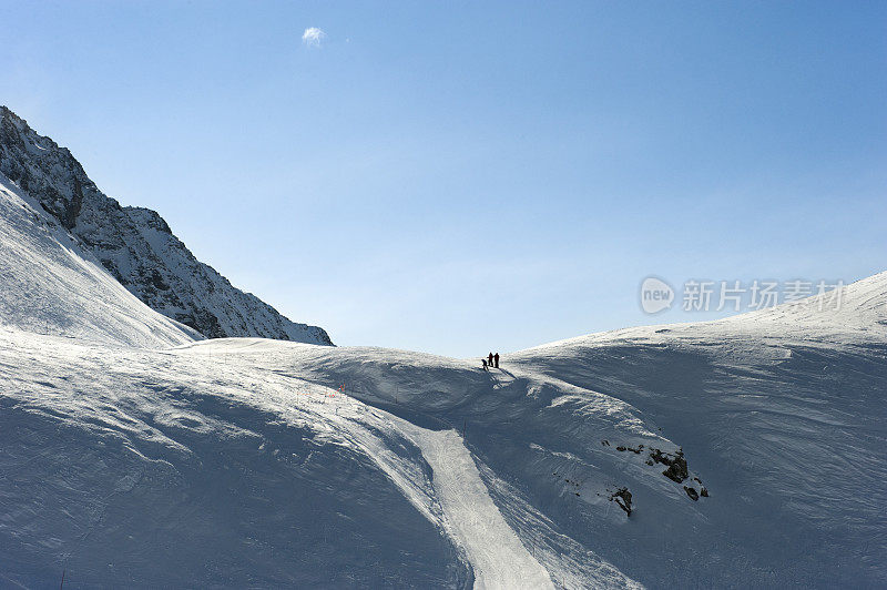 三个滑雪者在一个雪坡上