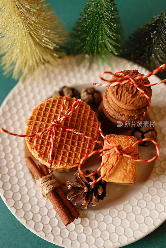 绳子系饼干和焦糖华夫饼在米色盘在绿色的背景，新年装饰品，小松树