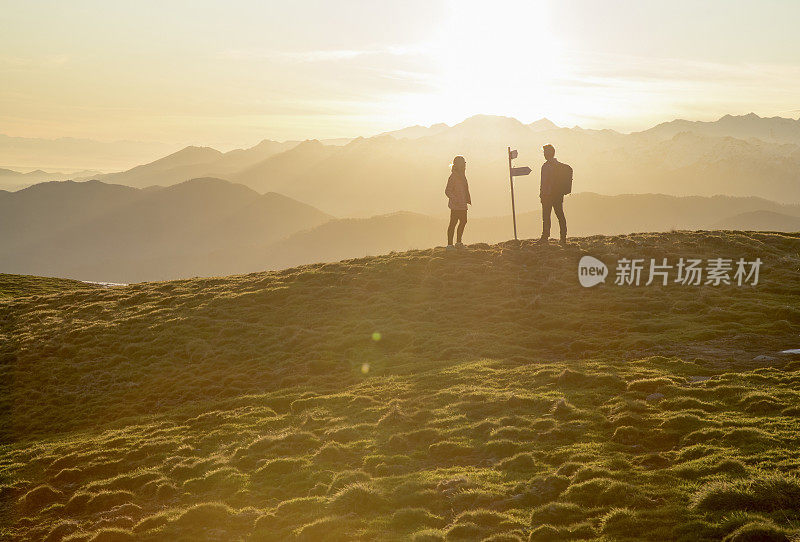 夫妇走在高高的草地上，路标