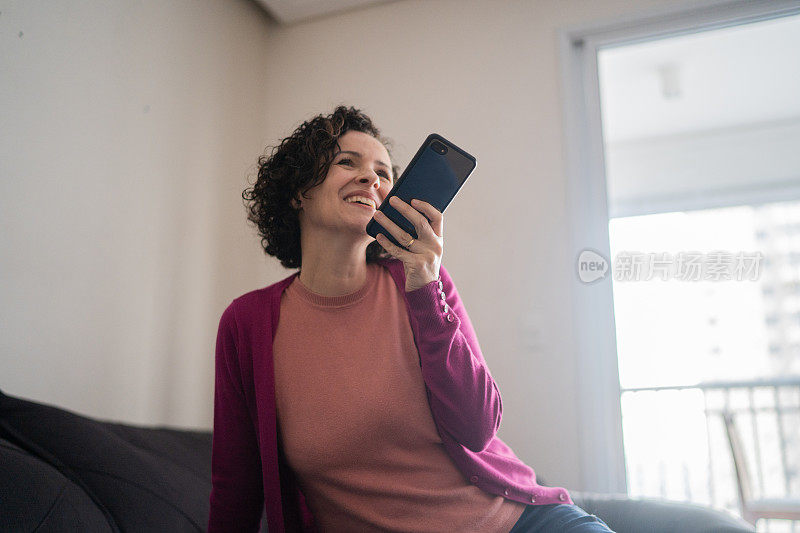 成熟的女人在家用电话发语音信息