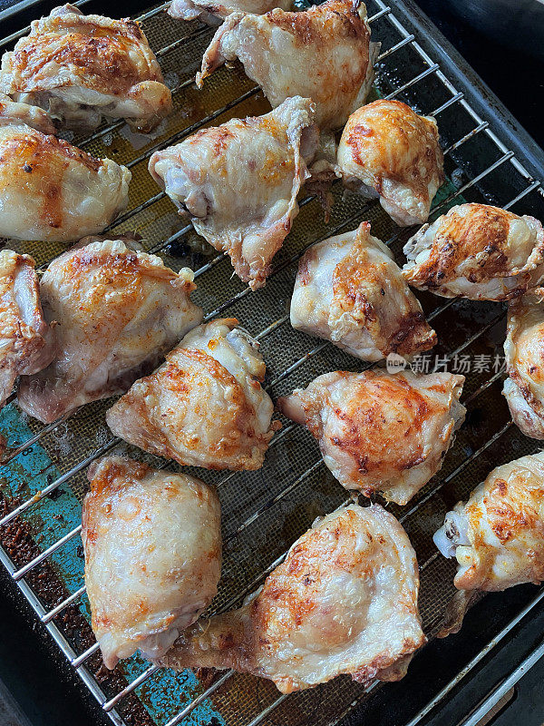 形象酥脆，金黄的鸡腿放在烤架上，皮脂肪烹饪和滴在下面的硅胶垫，俯瞰