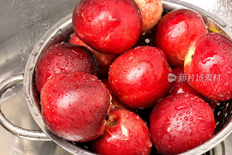 俯视图在洗过新鲜的成熟油桃在钢滤器。水滴在洗过的油桃上。