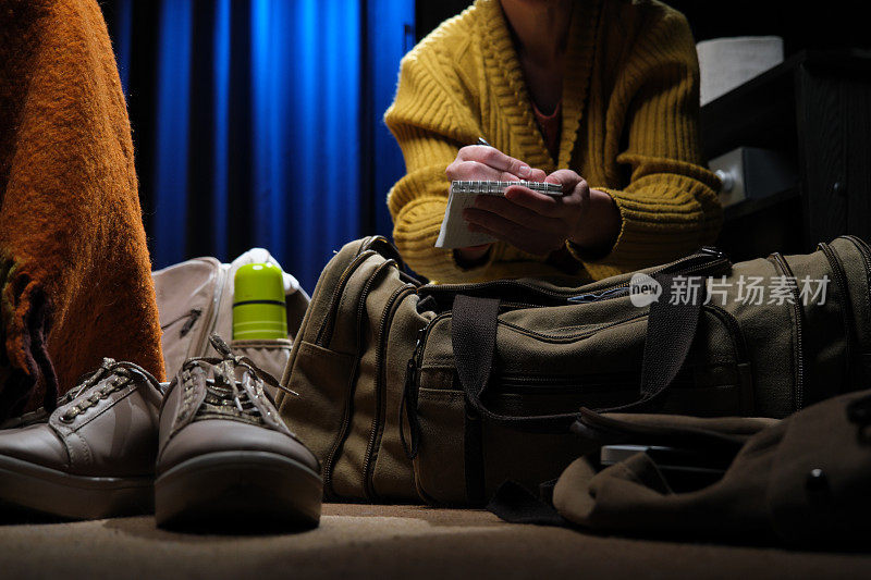 一个女人正坐在家里的地板上，为一次公路旅行打包行李