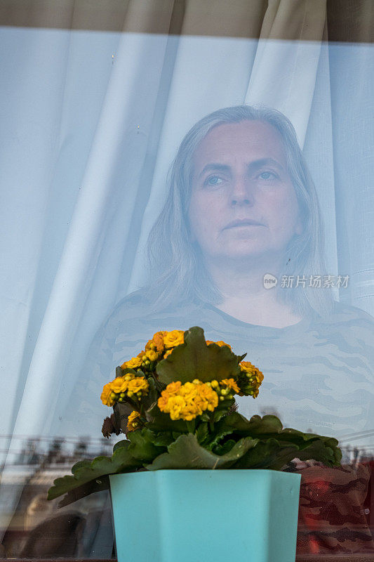 女人望着窗外的房子窗前的花