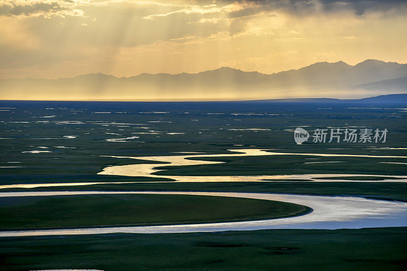 中国新疆维吾尔自治区，夕阳西下的草原上蜿蜒的河流