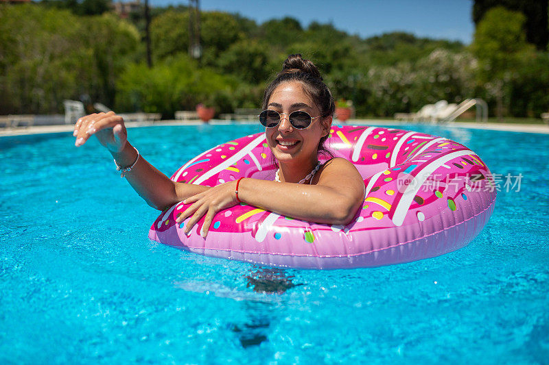 一个晒得黝黑的女孩在一个炎热的夏天的游泳池里玩得很开心
