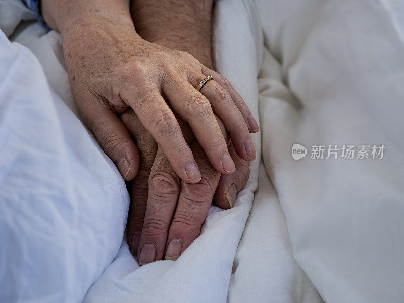 老夫妇手牵着手躺在床上