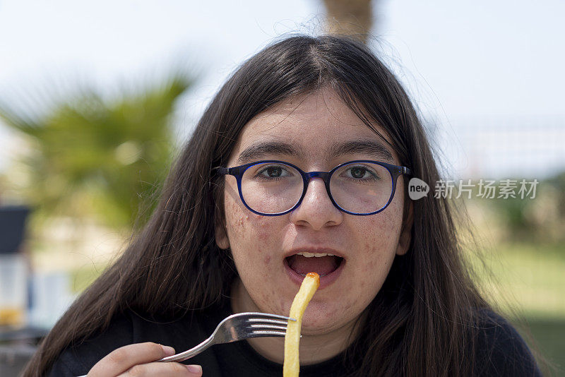 戴眼镜长痘痘的少女吃炸薯条