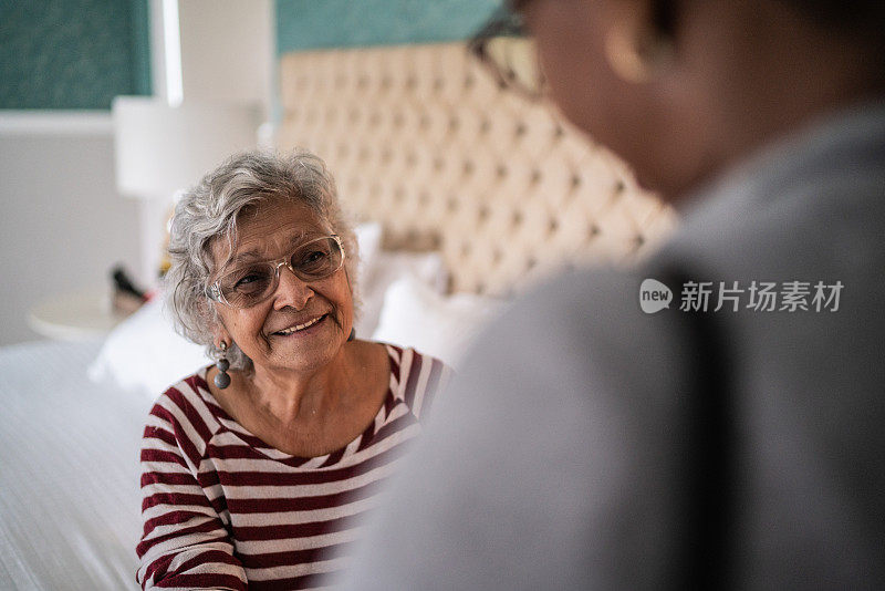 医生在卧室里和一位健康的老年女性谈话