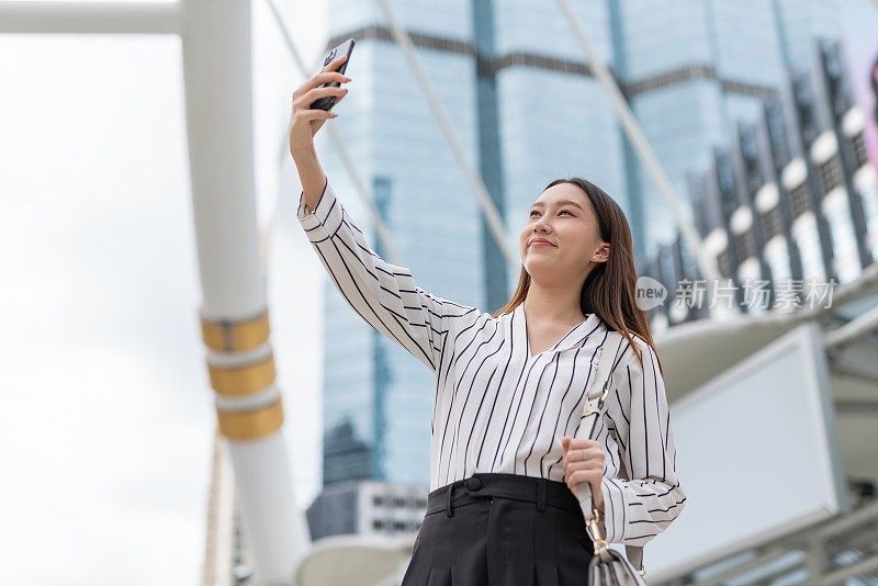 亚洲年轻漂亮的女商人在去商业区办公室的路上愉快地用手机自拍和视频通话