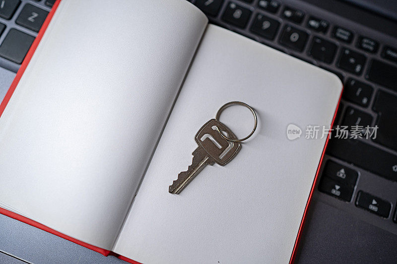 笔记本电脑和钥匙。电脑上的空白便签簿和房子钥匙。为房地产介绍，购买自己的房子。作为演示背景