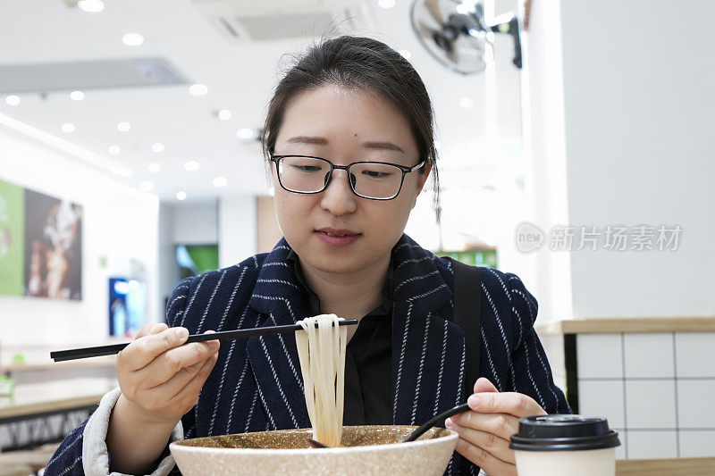 亚洲女性在店里吃素面