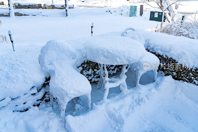 院子里的椅子和桌子被雪覆盖着