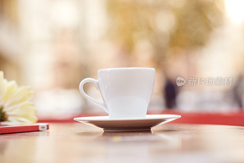 白色模拟杯咖啡在桌子外面的前景散景背景。副本的空间。秋天的畅快。广告场所