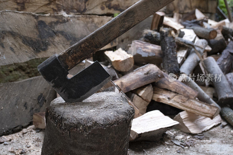 劈柴的斧子卡在木头里了。