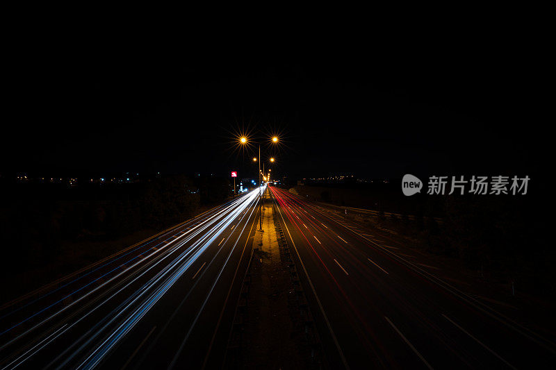 夜晚高速公路上车水马龙，车灯拉长。长时间曝光