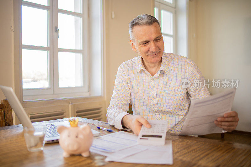 成熟的男人在处理账单和家庭财务时使用计算器