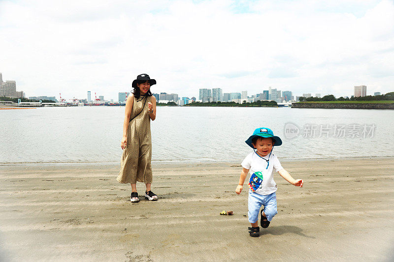 年轻的母亲带着她的小儿子在海边散步