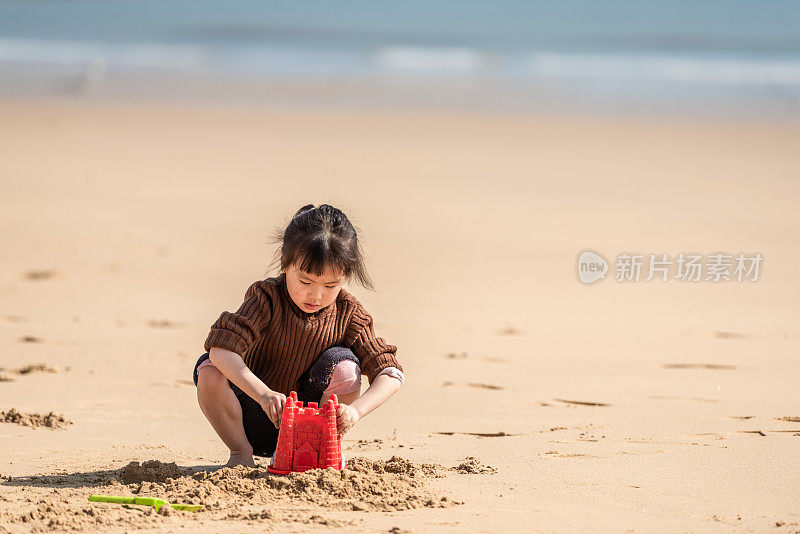 一个中国小女孩在沙滩上玩沙子