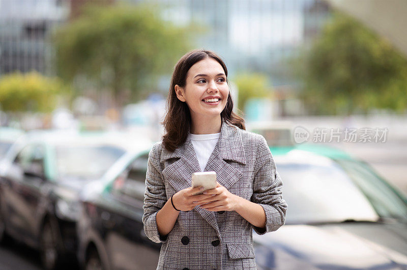 用手机发短信的年轻女商人在市区户外散步