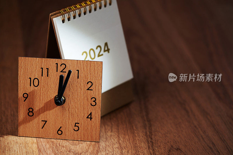 2024台历和12点钟方向的挂钟放在木桌上