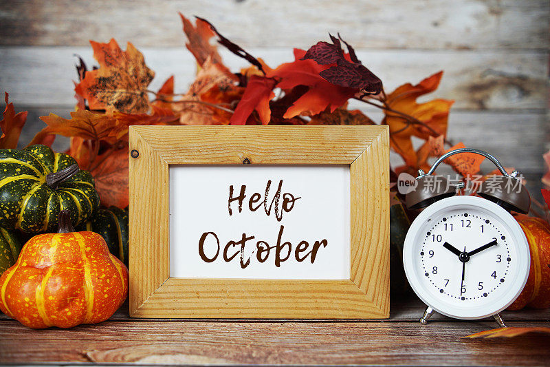 你好，十月的短信写在黑板上，木底装饰着南瓜和秋天的枫叶