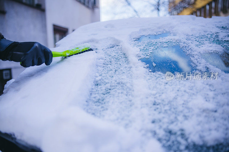 年轻人正在清除汽车上的积雪