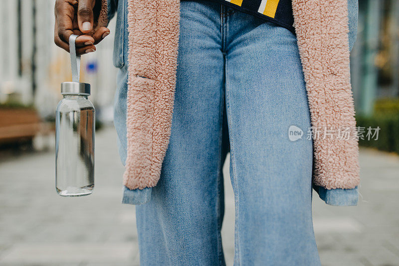 漂亮的黑人女人拿着装满水的塑料容器