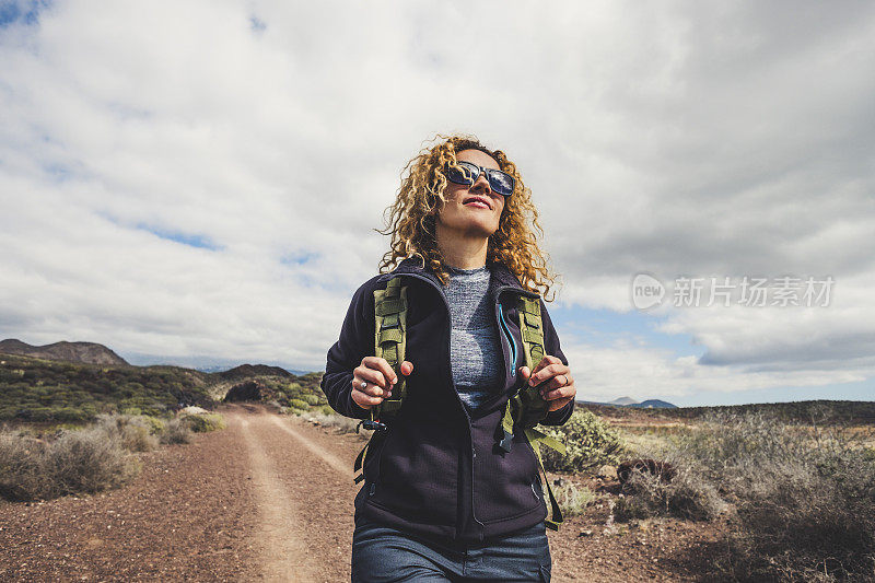 年轻美丽的女人背着背包和徒步旅行的衣服在山里徒步旅行。健康和积极的生活方式。女性的自然背景与岩石背景。探险旅游休闲活动