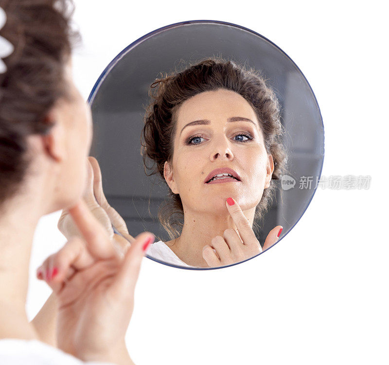 一位中年妇女看着镜子里自己的脸