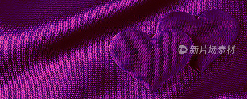 浪漫的背景(紫色绸缎上的一对紫心)