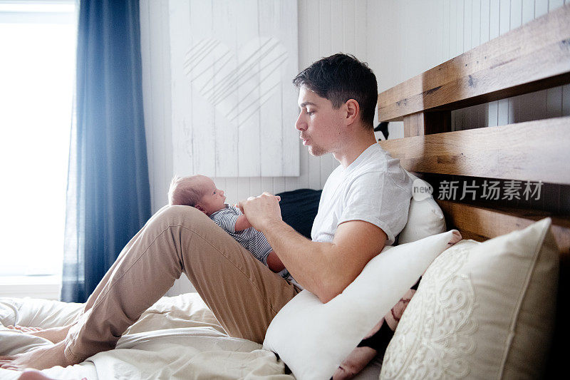 刚出生的男婴和他的父亲在一间卧室里