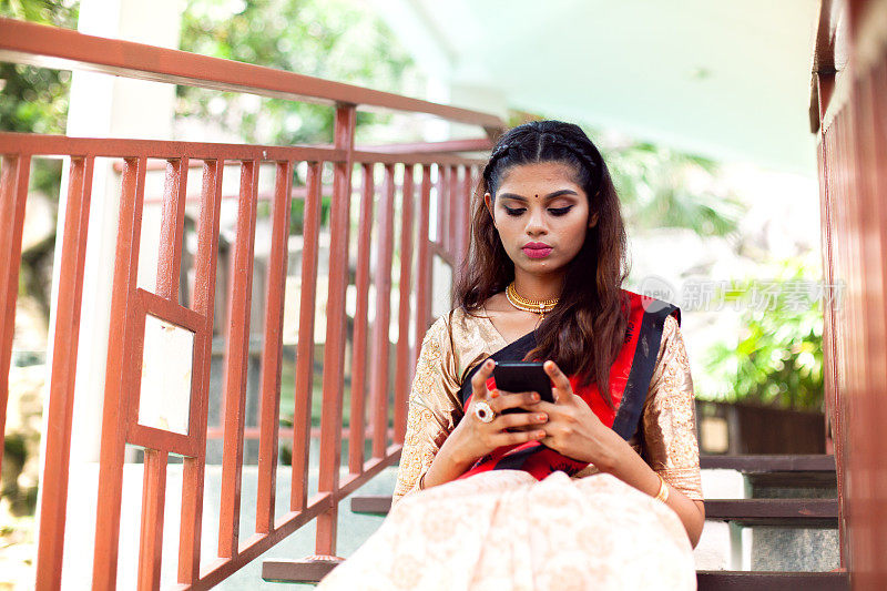 年轻的印度女子在使用智能手机纱丽(纱丽)