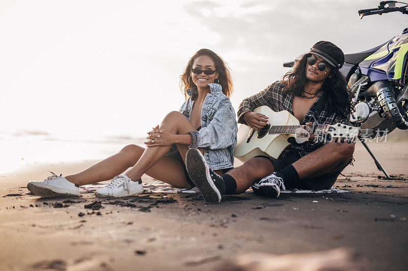 一个家伙在沙滩上给他女朋友弹吉他