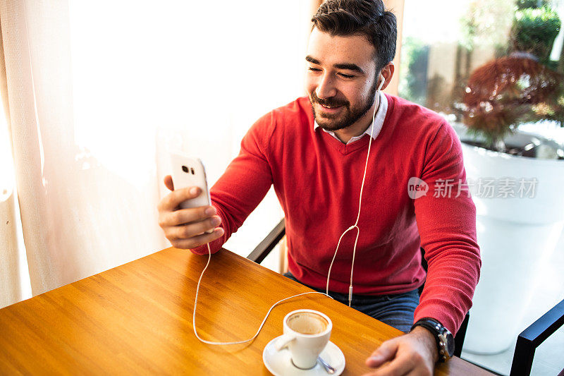 男人坐在café喝咖啡和使用手机