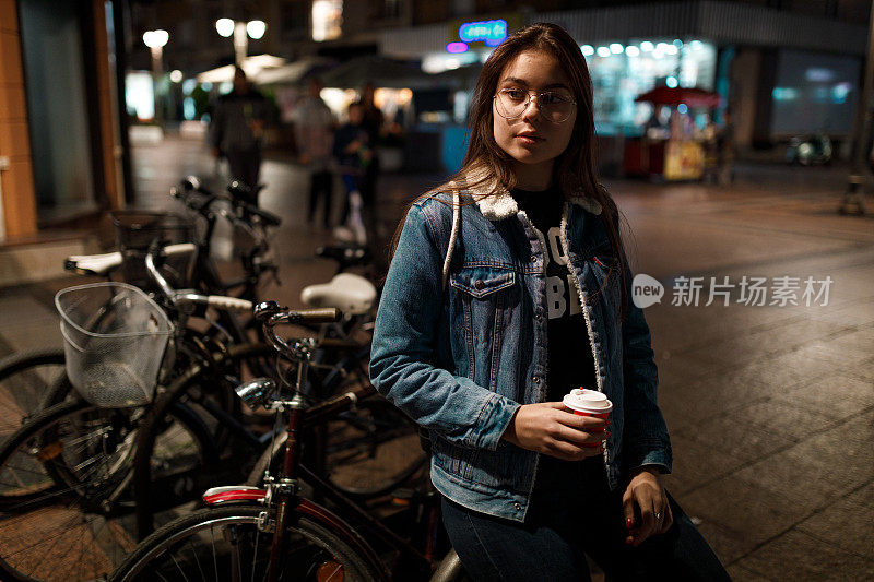 冬天的夜晚，一个十几岁的女孩拿着一个咖啡杯